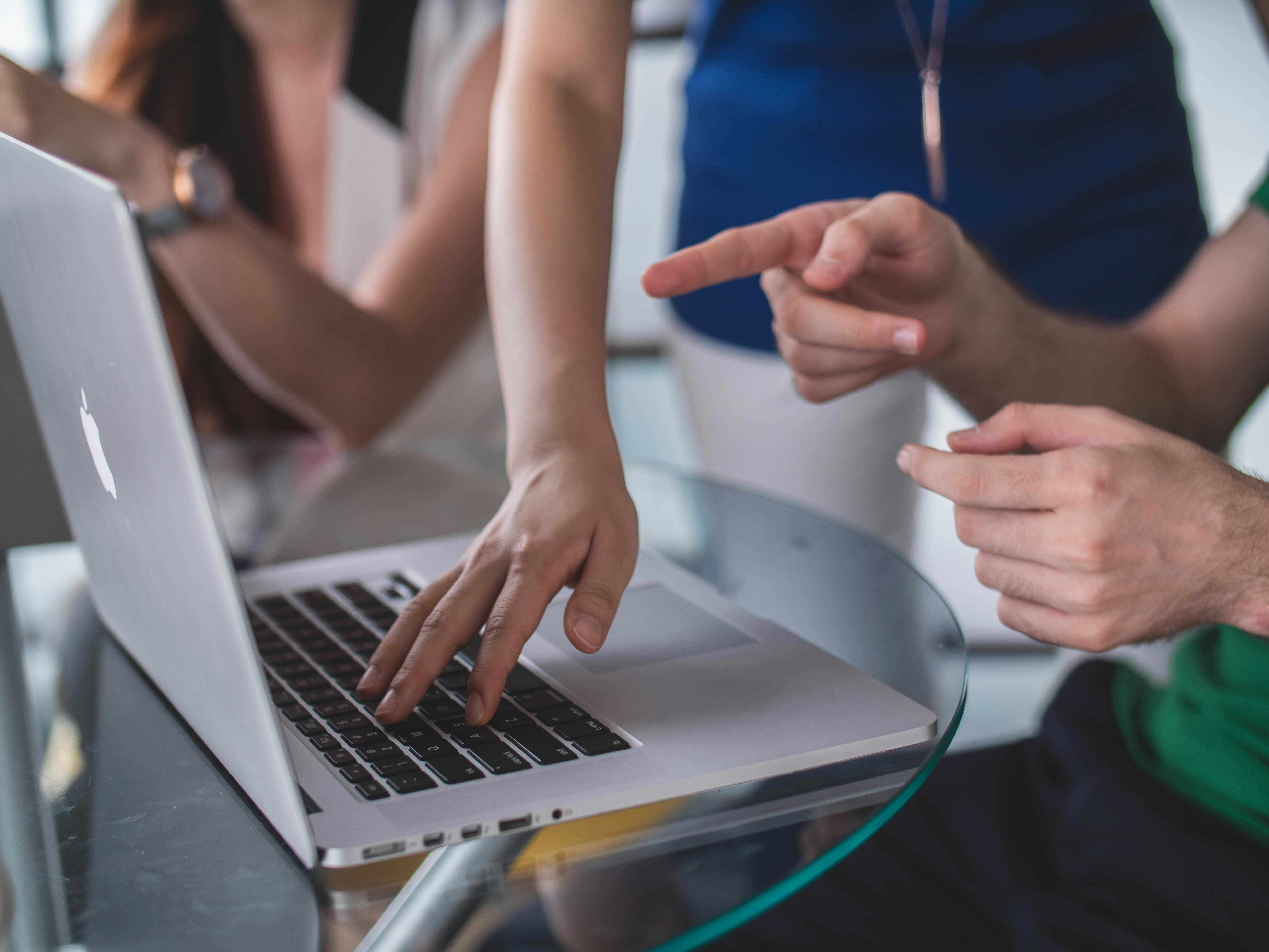 pessoa digitando e outra apontando para notebook estão trabalhando com economia colaborativa 